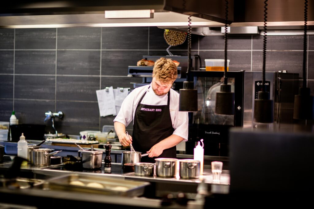 pexels-photo-2544829-2544829 Chef preparing meal in a modern kitchen with various cookware.